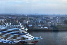 Fotografie von Hilmar Sundermann. Panoramablick von oben auf Hamburger Hafen und Elbe mit großem Kreuzfahrtschiff im Vordergrund sowie einem weiteren im Hintergrund am Bildrand unter Sonnenuntergangshimmel. Spiegelung der Elbe mit untergehender Sonne am gegenüber liegenden Bildrand.