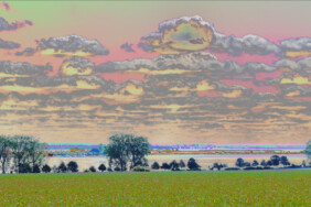 Fotografie von Hilmar Sundermann in surrealer Bearbeitung mit hellen, pastellartigen Grün- und Rosatönen. Panorama-Blick über die Landschaft mit weitem Feld und die dahinterliegende Kirchsee; am Ufer Baumgruppen; darüber der bewölkte Himmel.